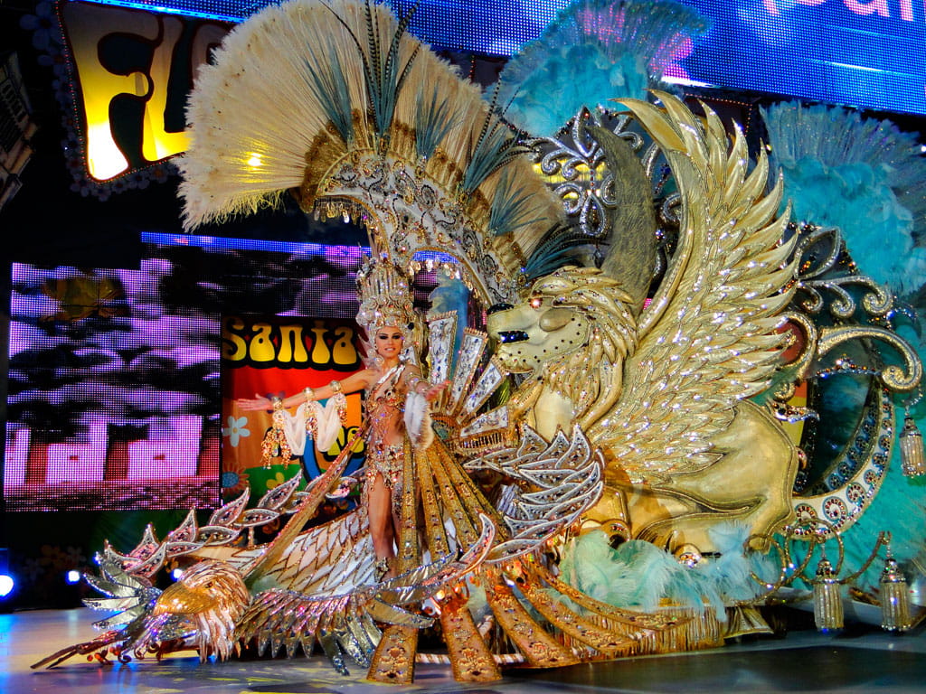 Character in golden festive costume with feather ornaments and winged lion in Santa Cruz de Tenerife.