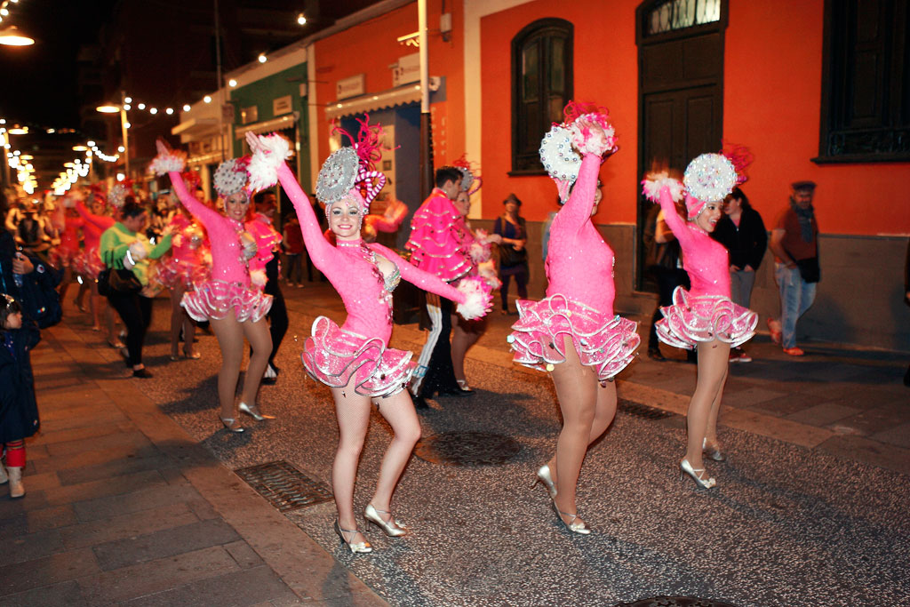 Dancers in pink costumes parade at a night carnival in Tenerife.