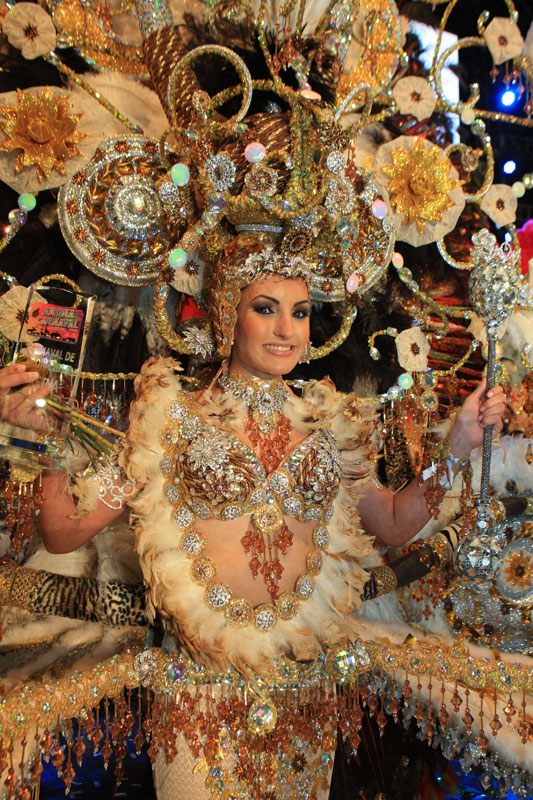 Person in detailed carnival costume in Tenerife, surrounded by shiny ornaments.