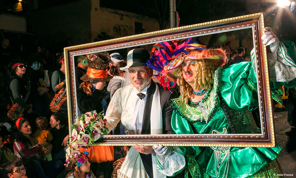 People in colourful costumes pose behind a frame at the Tenerife carnival.