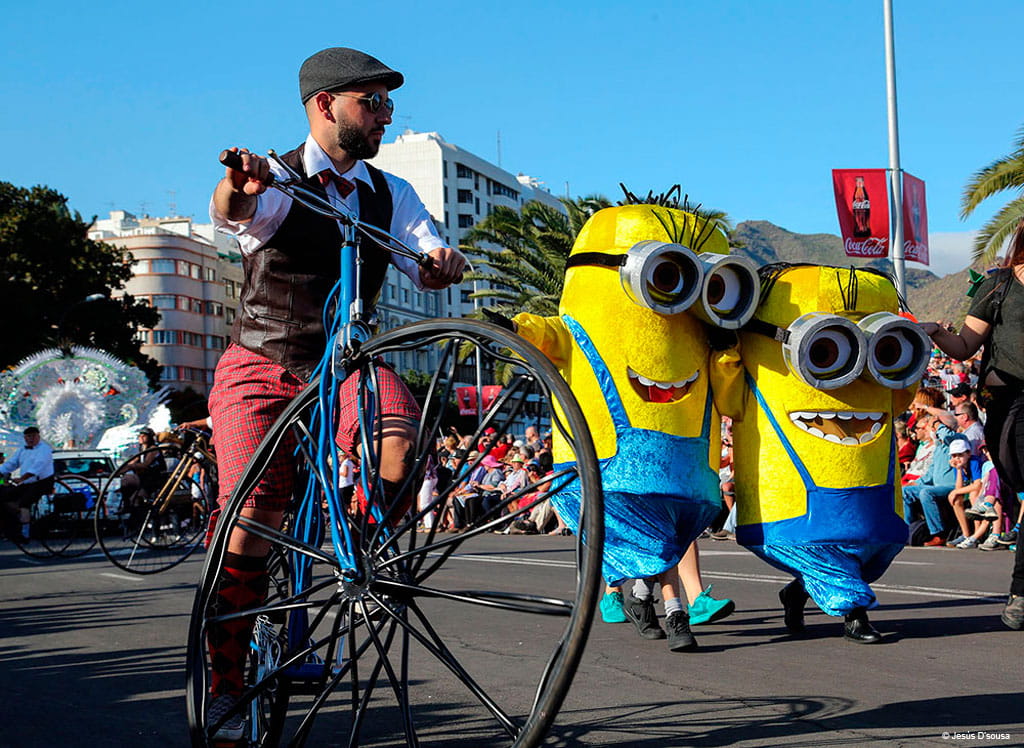 Parade with people dressed up as yellow characters and cyclist on an old bicycle in Tenerife.