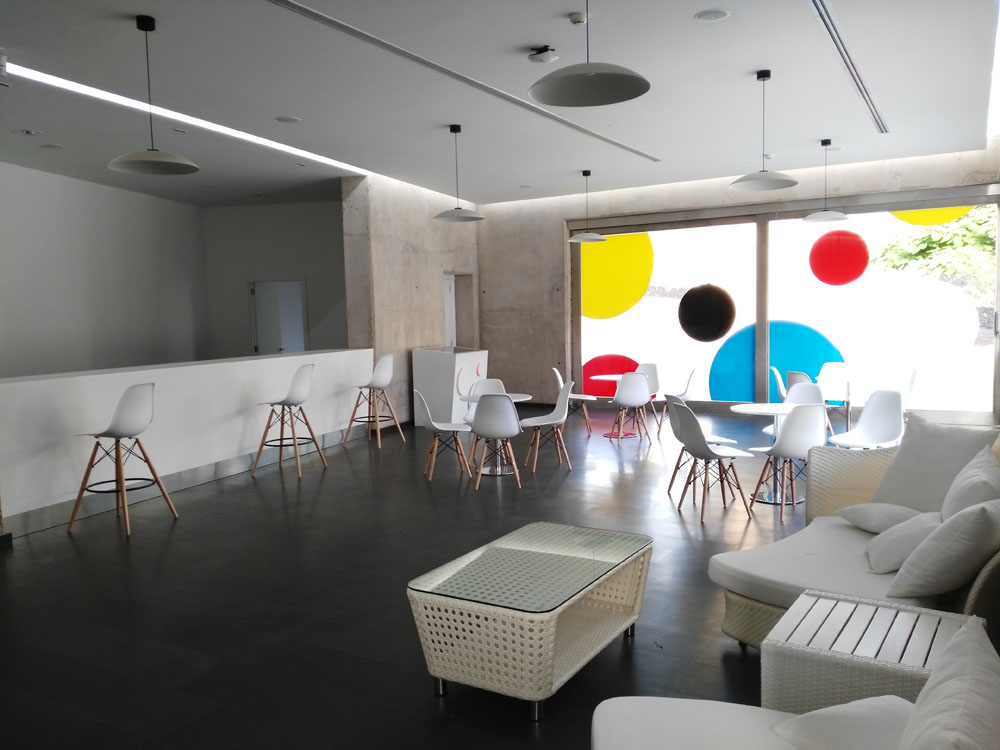 Modern seating area with chairs and tables next to a bay window in Tenerife.