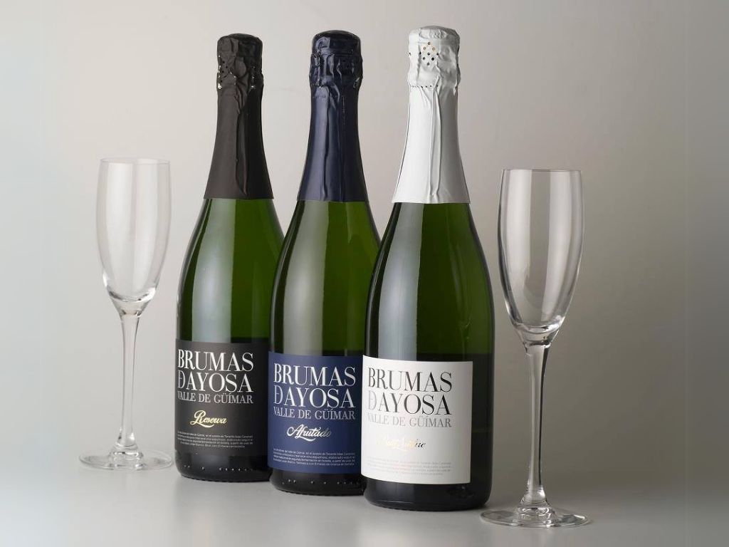 Bottles of Brumas de Ayosa sparkling wine from the Güímar Valley next to glasses.