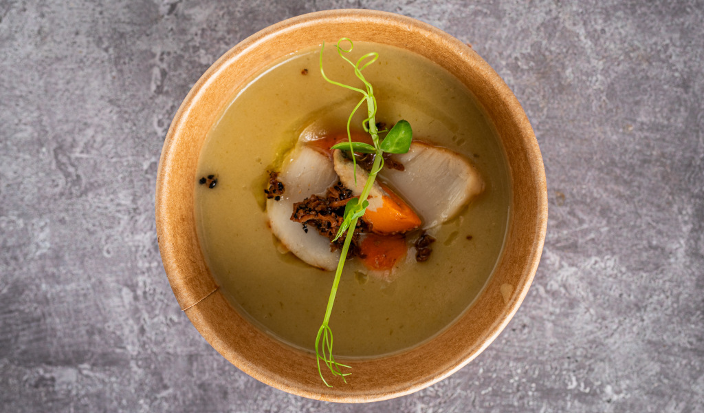 Creamy soup with vegetables and green sprouts in a bowl on a stone table in Tenerife.