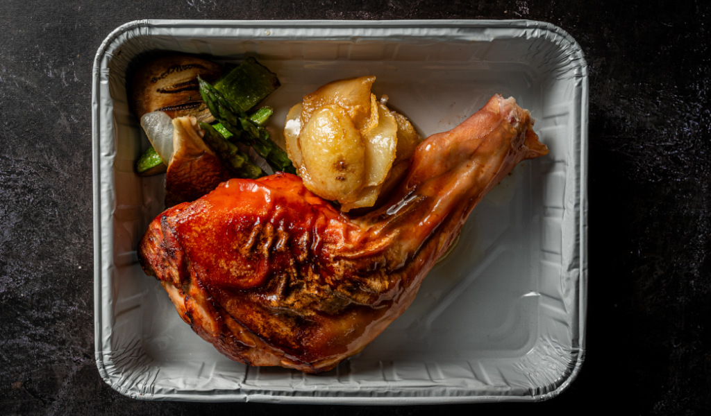 Roast chicken with vegetables and potatoes on an aluminum tray in Tenerife.