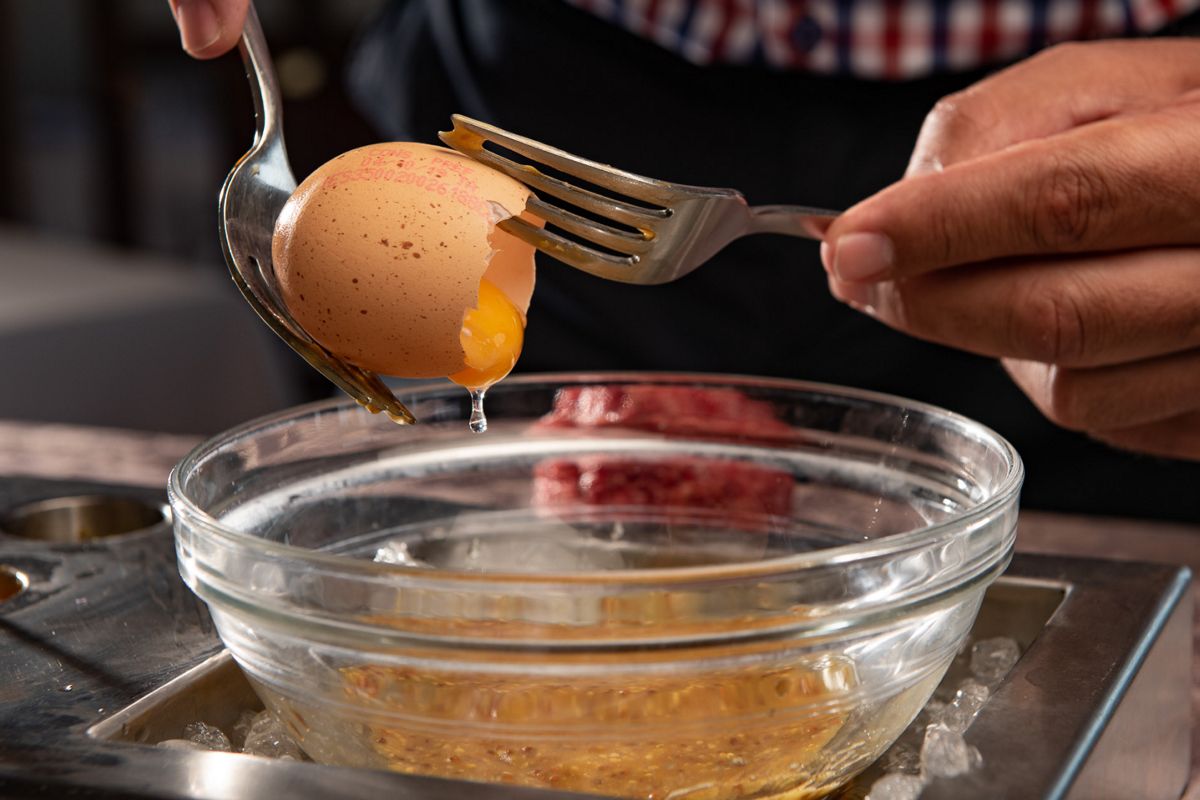 Egg being opened with fork and spoon over a bowl in Tenerife.