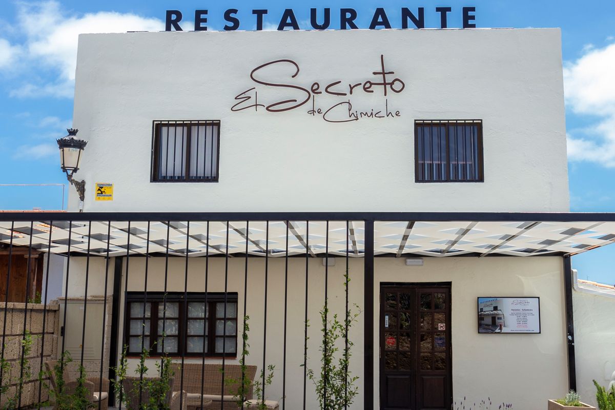 El Secreto de Chimiche Restaurant in Tenerife with a sign on a white façade.