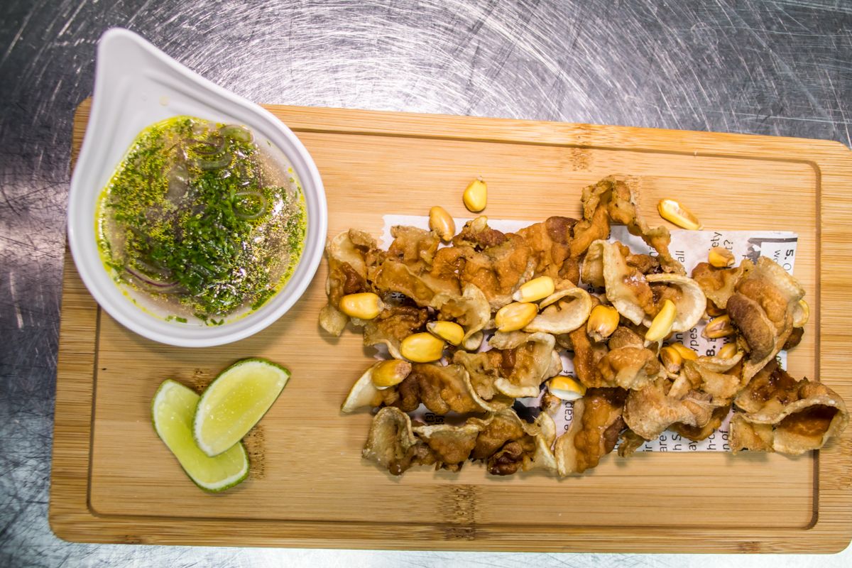 Crispy pork rinds and corn with green sauce accompanied by lime wedges in Tenerife.
