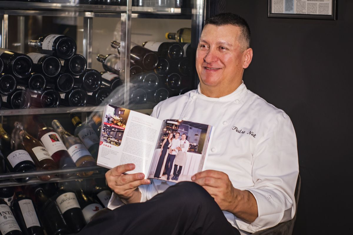 Chef oenologist smiles while holding a magazine in a winery in Tenerife.