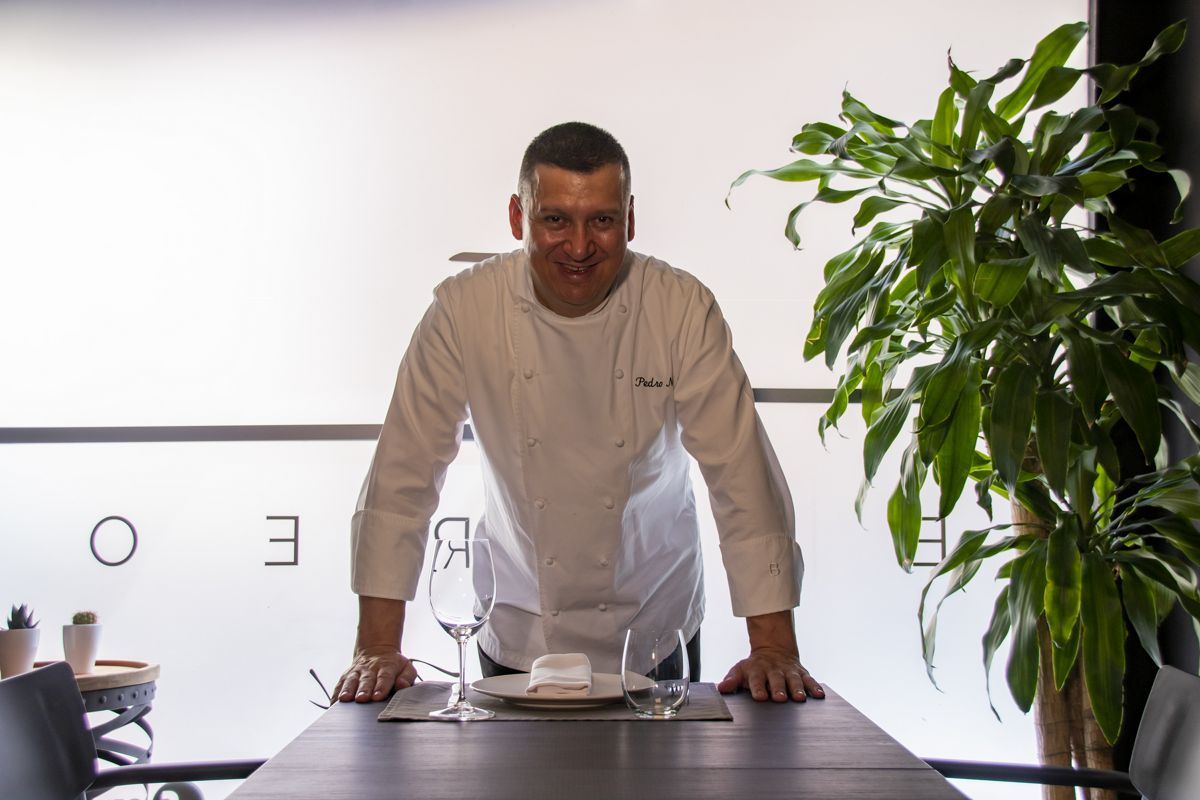 Chef in kitchen with plant and table set in restaurant in Tenerife.