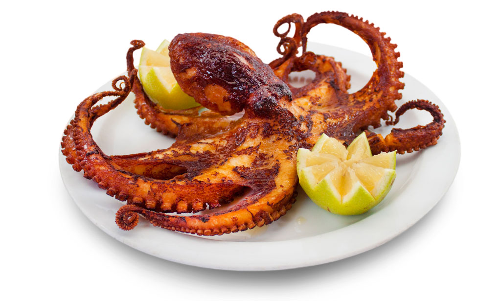 Grilled octopus served with lemon wedges on a white plate in Tenerife.