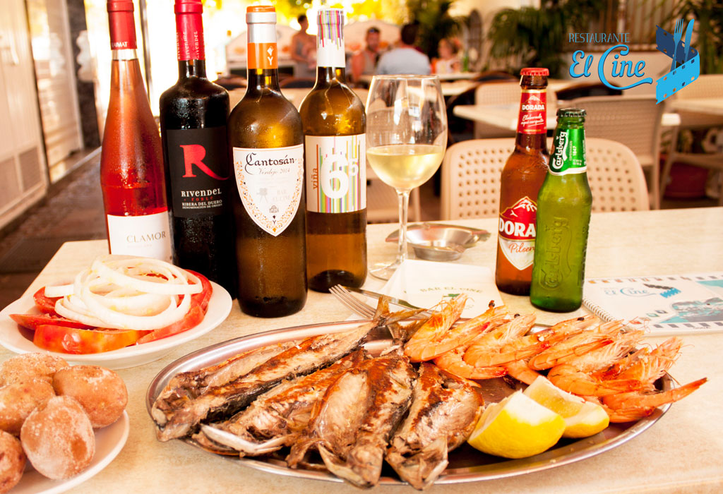 Fish and prawn dish with bottles of wine and beer at El Cine Restaurant, Tenerife.