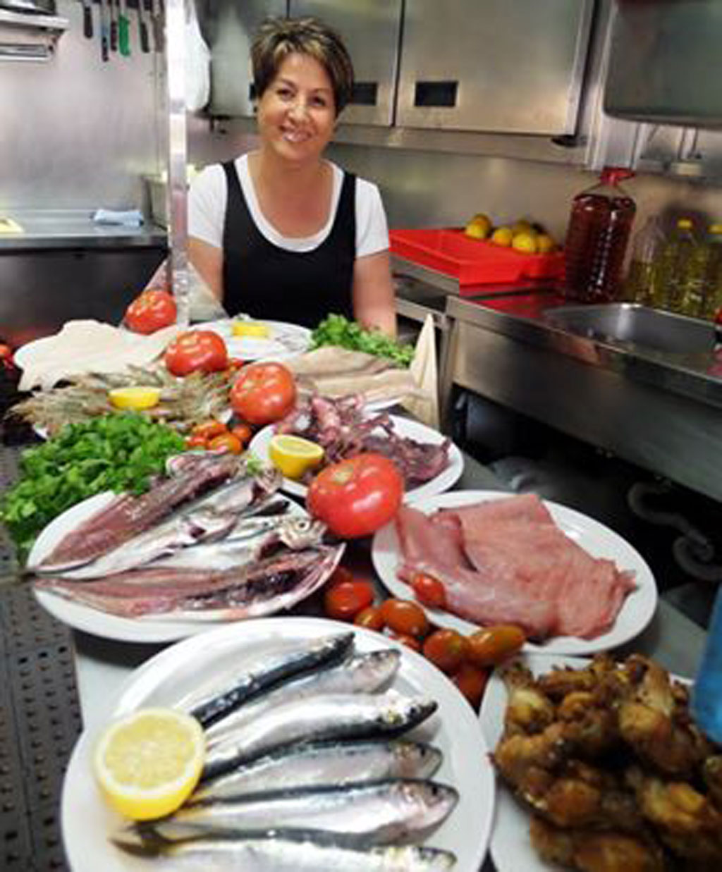 Person in kitchen with fish, tomato and lemon dishes in Tenerife.