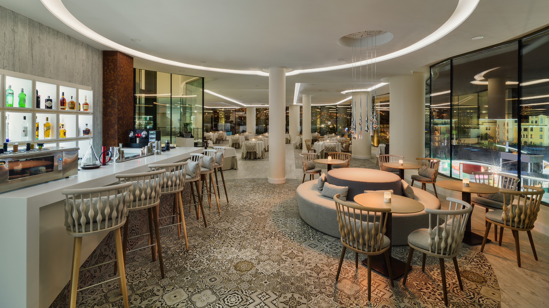 Interior of an elegant restaurant in Tenerife, with an illuminated bar and tables with chairs.