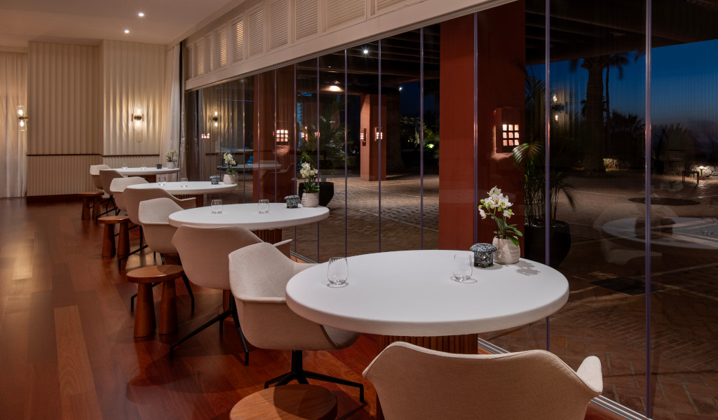 Dining tables and chairs next to large windows in an elegant restaurant in Tenerife.