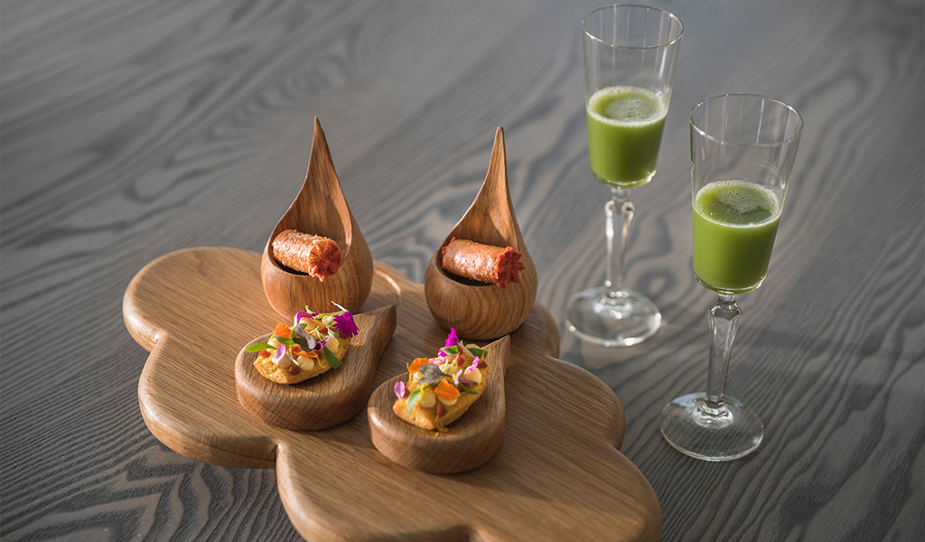 Variety of gourmet appetizers and glasses with green juice on a board in Tenerife.