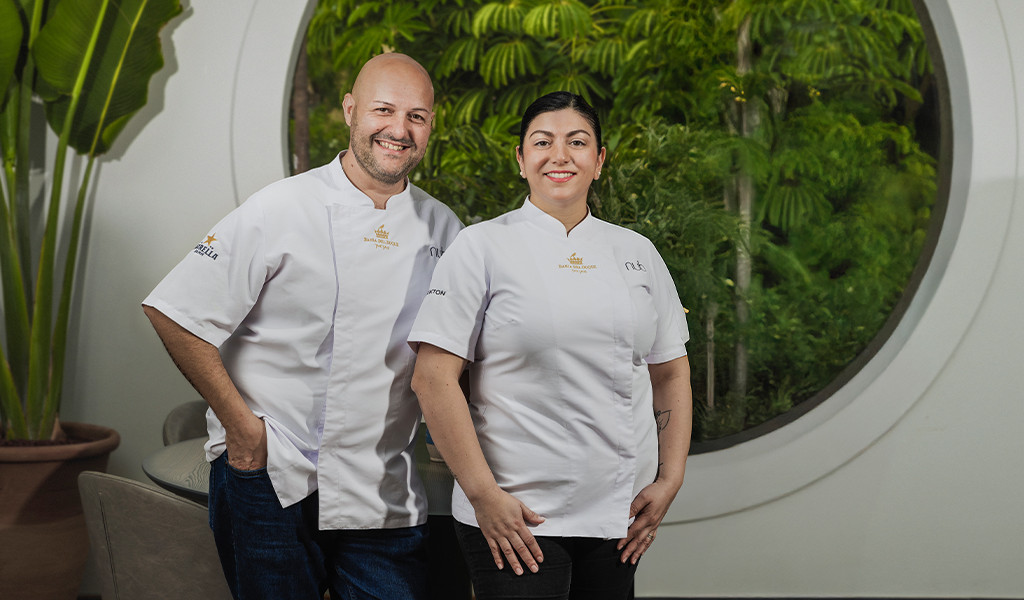 Two chefs smiling in white uniforms in front of a garden in Tenerife.