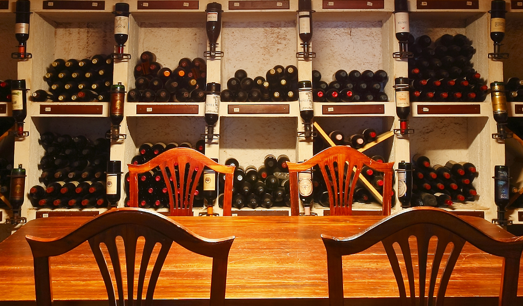 Wooden table and chairs in front of a shelf full of bottles of wine in Tenerife.