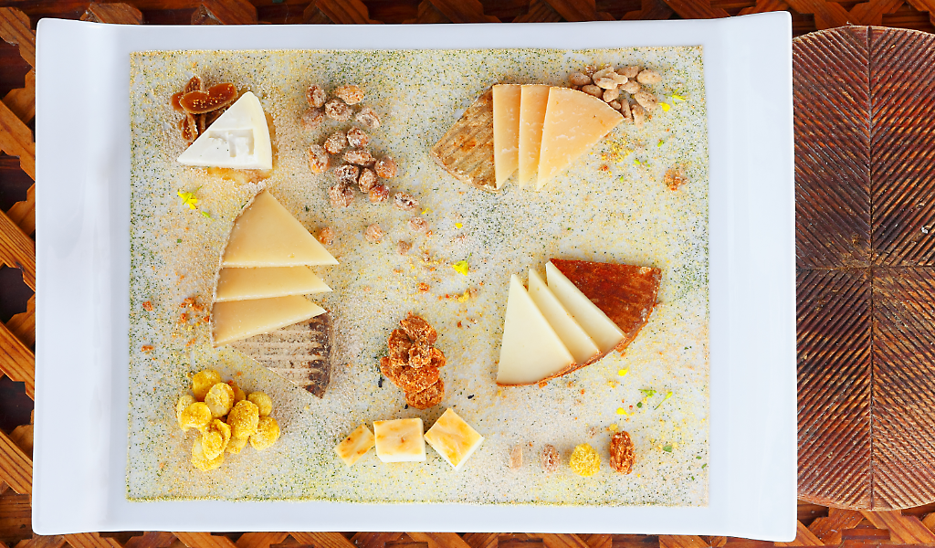 A variety of cheeses on a plate in Tenerife, accompanied by nuts and corn.