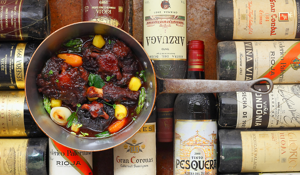 Meat stew in a pan surrounded by bottles of wine in Tenerife.