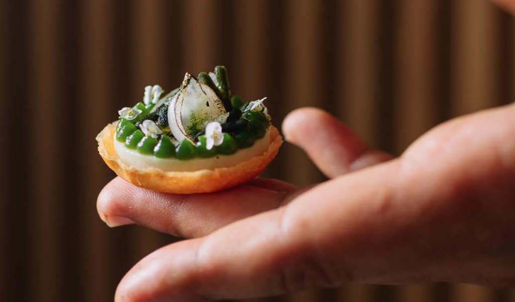 Gourmet bite in hand, decorated with pickled onion and herbs in Tenerife.