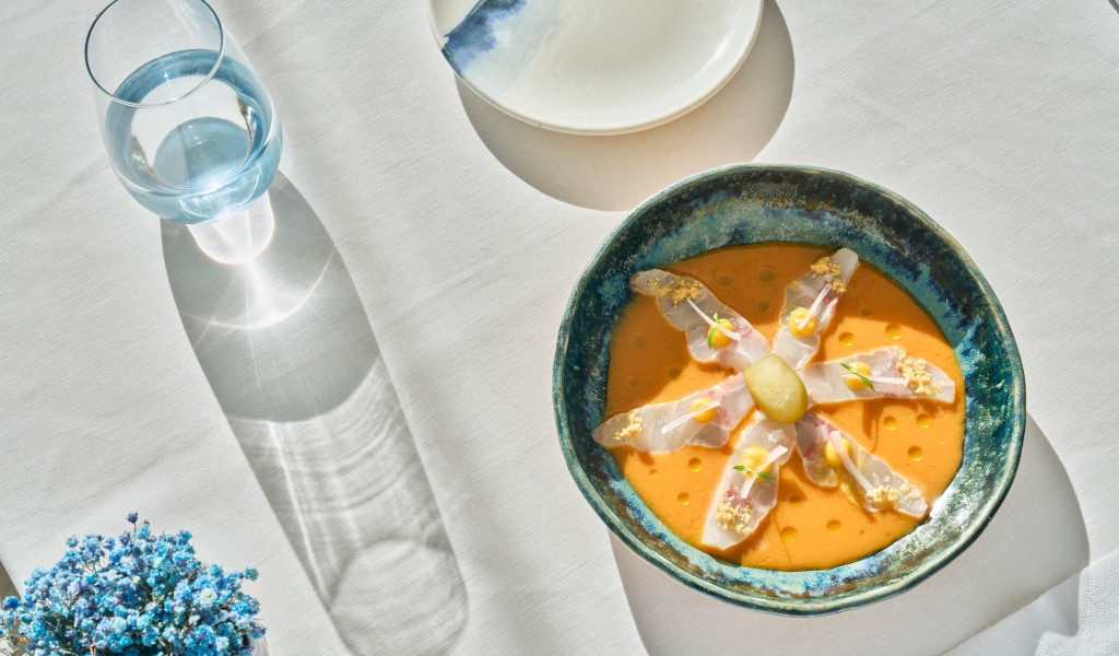 Plate of creamy orange soup with decorative flowers on an elegant table in Tenerife.