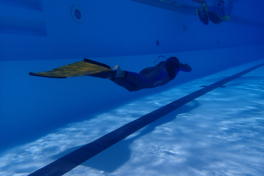 Person diving in a pool in Tenerife with yellow fins.
