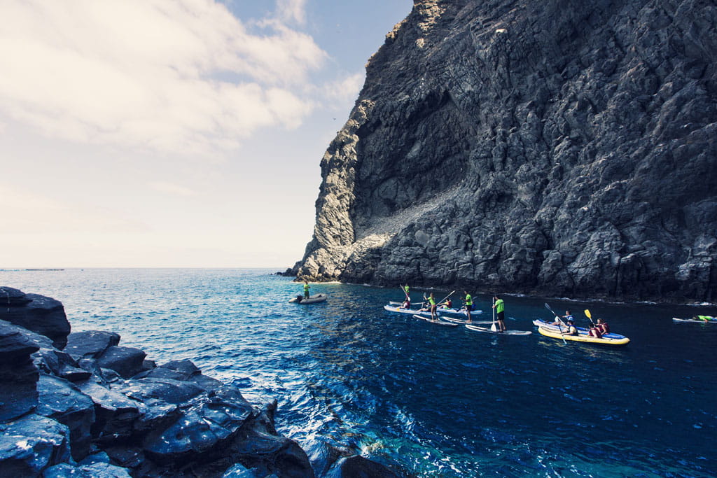 People paddle boarding near a cliff in Tenerife.