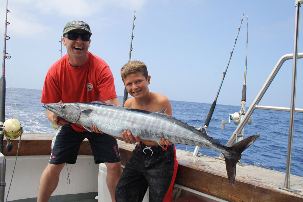 People holding a big fish on a fishing boat in Tenerife.