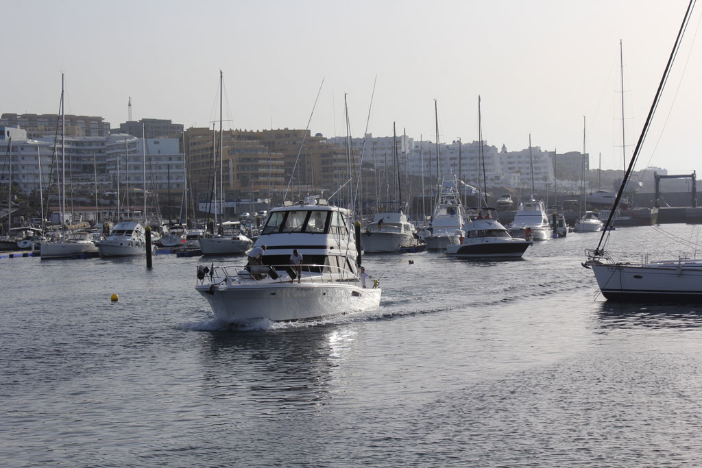 Boats in the port of Los Cristianos, Tenerife, with buildings in the background.