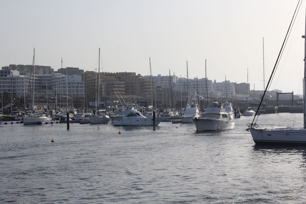 Boats in the port of Los Cristianos, Tenerife, with buildings in the background.