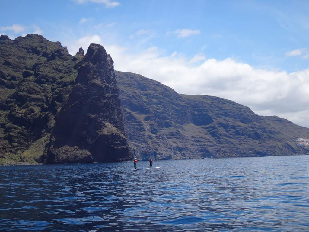 People paddle surfing in front of the cliffs of Los Gigantes, Tenerife.