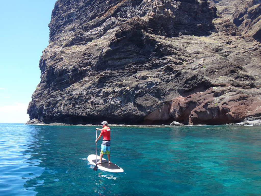 Person paddle boarding near a cliff in Los Gigantes, Tenerife.