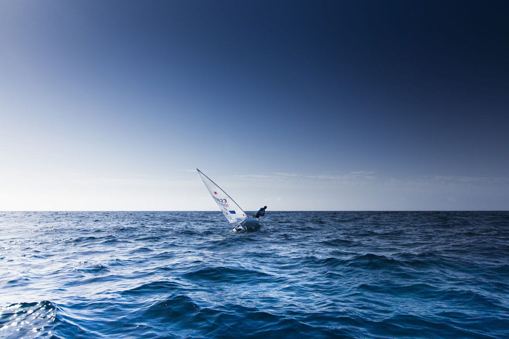 Person sailing on a small sailboat in the sea of Tenerife.