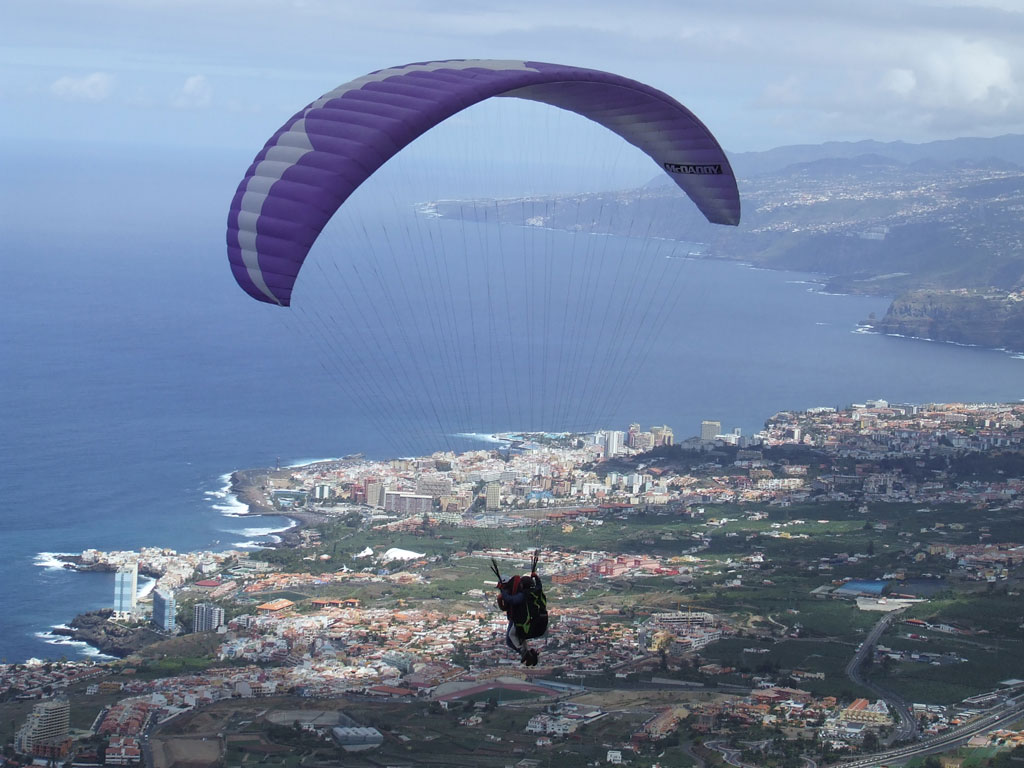 Paragliding flying over the coast of Tenerife with the Atlantic Ocean in the background.