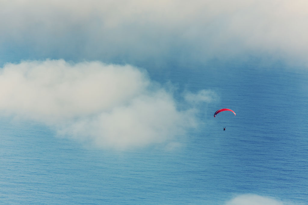 Paragliding over the ocean in Tenerife among scattered clouds.
