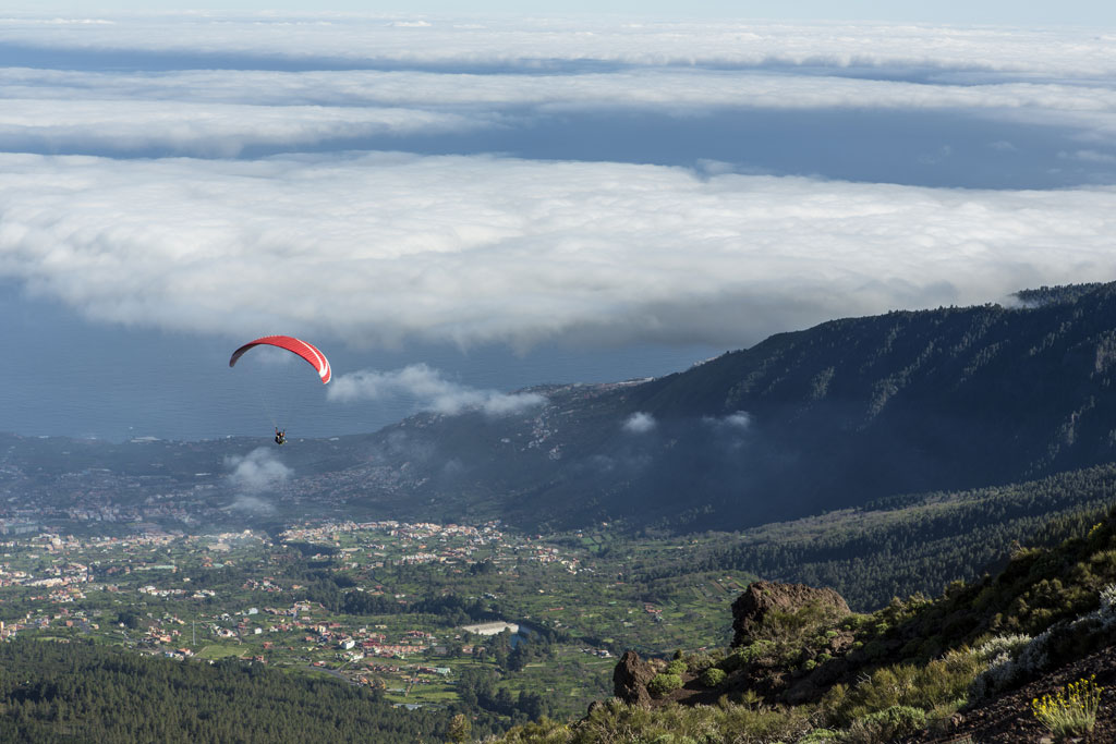 Paragliding flying over the valley in Tenerife with low clouds.