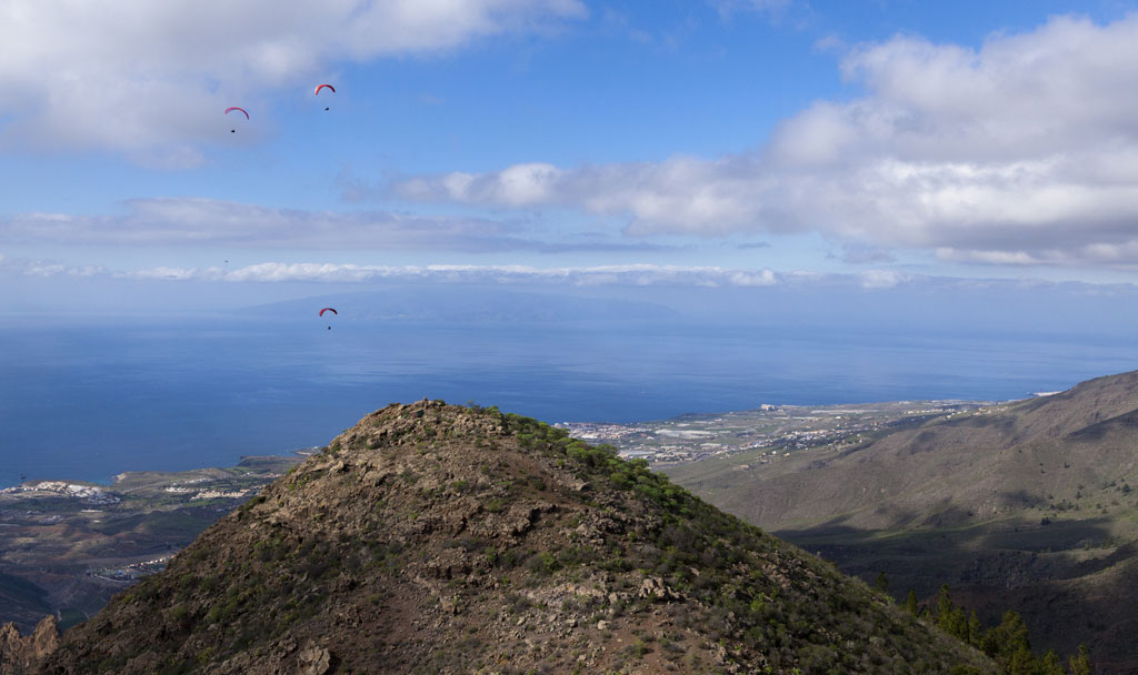 Paragliders flying over a mountain in Tenerife overlooking the ocean.