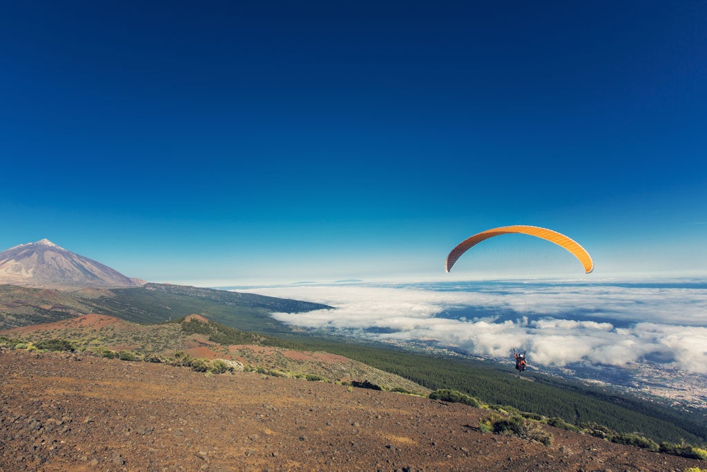 Paraglider flying near Mount Teide in Tenerife under clear skies.