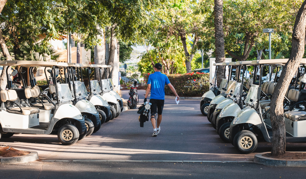 Man walks between parked golf carts in Tenerife.