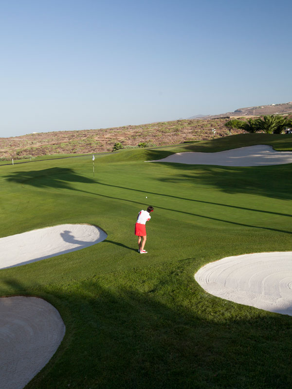 Golf player on the Abama course in Tenerife, near the hole and a bunker.