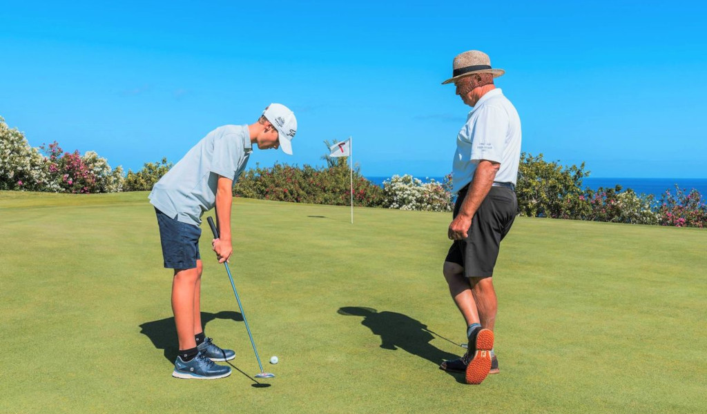 Child playing golf with adult in the background, Tenerife.