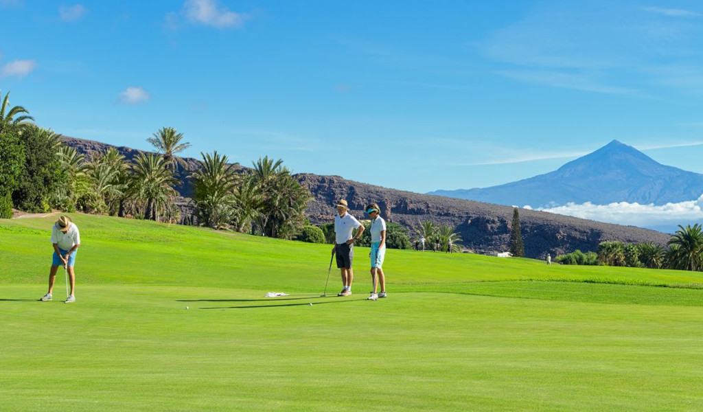 Golfers on a course in Tenerife with Mount Teide in the background.
