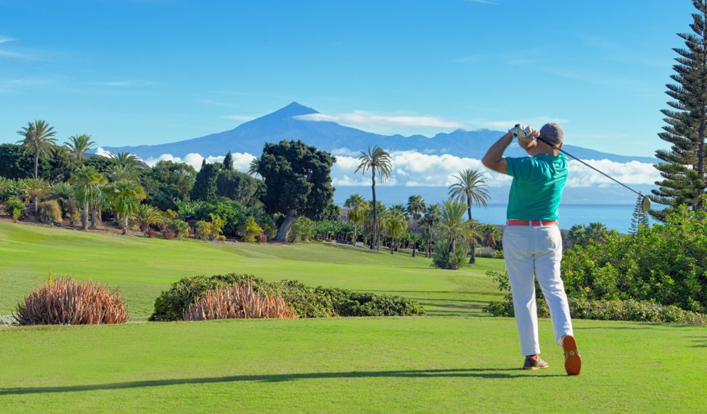 Golfer in action with Mount Teide in the background in Tenerife.