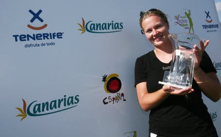 Person holding a trophy in front of a panel with logos of Tenerife and the Canary Islands.