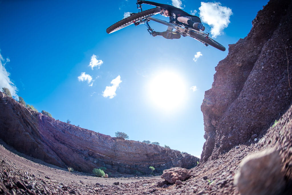 Cyclist in extreme jump in a canyon in Tenerife under clear skies.