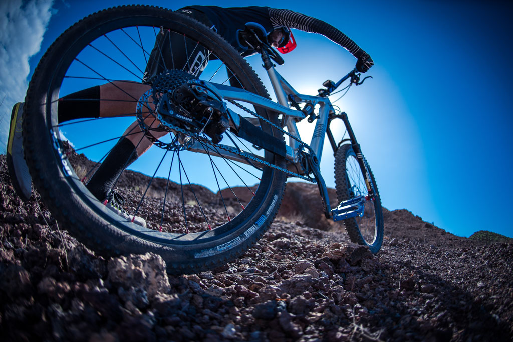 Mountain bike cyclist over rocky terrain in Tenerife under blue skies.