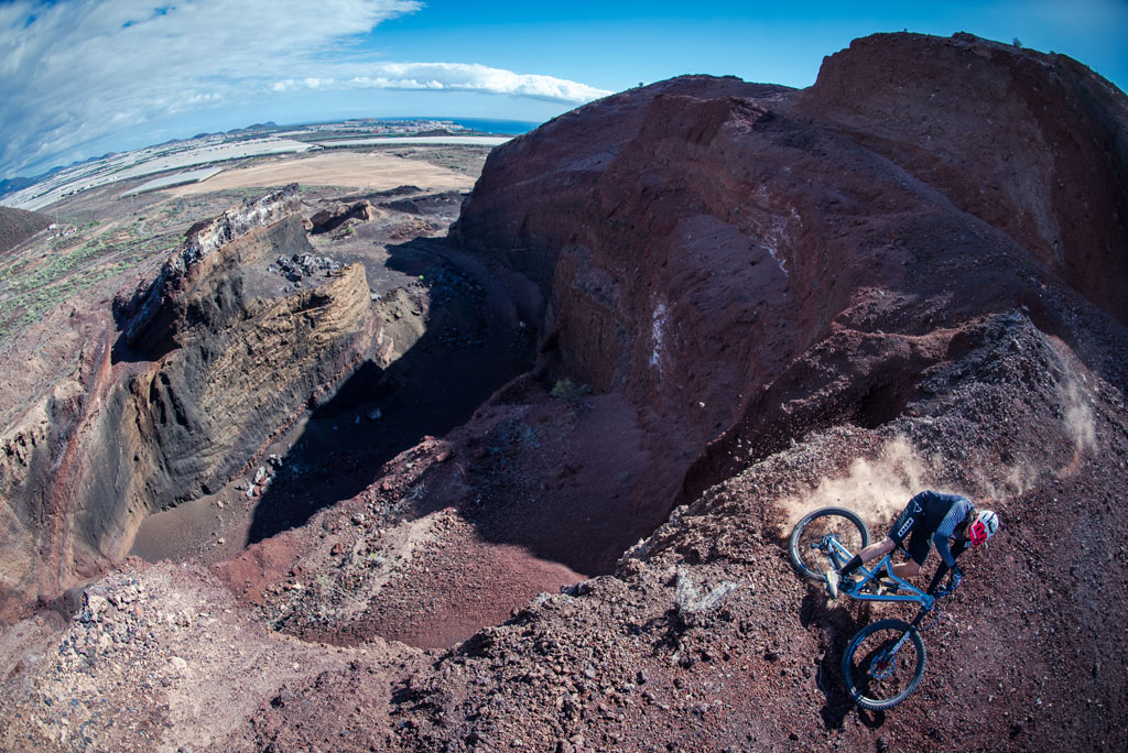 Cyclist descending a hillside in a quarry in Tenerife, overlooking the sea.