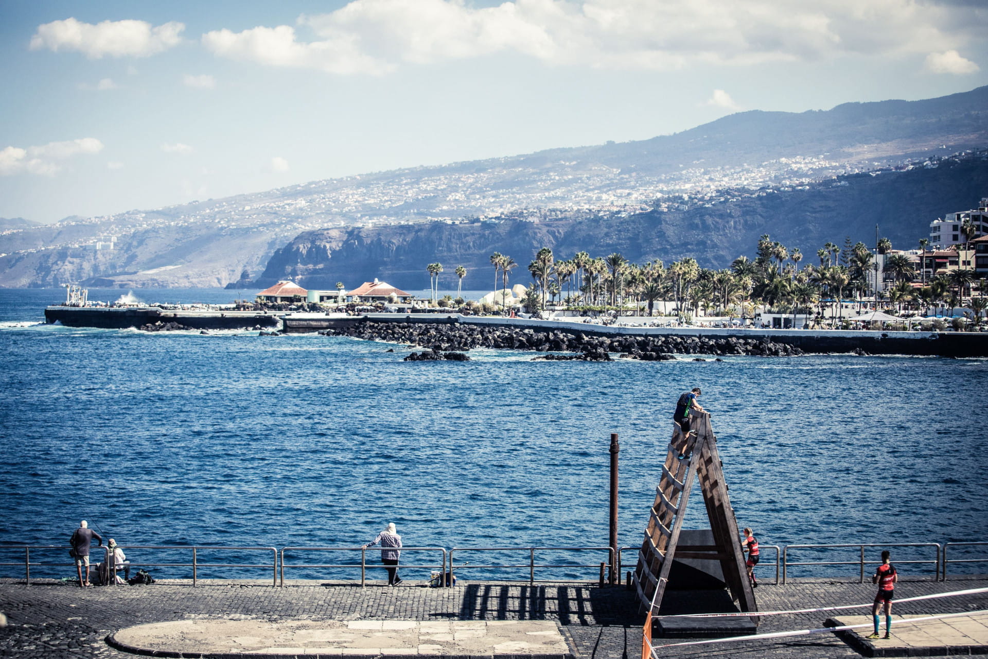 View of the harbour and promenade in Puerto de la Cruz, Tenerife, with mountains in the background.