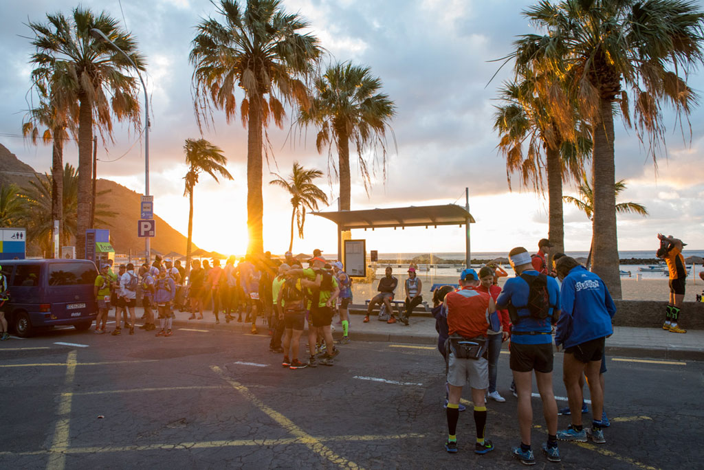Group of people gathered on the promenade of Las Teresitas at dawn.